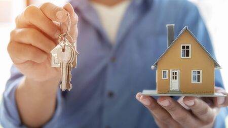 Real estate agent holding a key and asking costumer for contract to buy, get insurance or loan real estate or property.