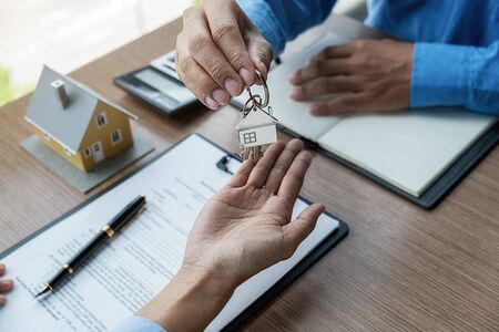 Real estate agent holding a key and asking costumer for contract to buy, get insurance or loan real...