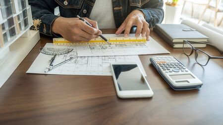 Architect or Engineer working in office with engineering tools, blueprint and building model. Construction concept.の写真素材