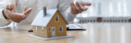 House model with agent asking costumer for contract to buy, get insurance or loan real estate or property.の写真素材