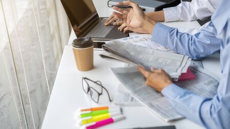 Young unemployed is searching for a job in the newspaper and laptop. Interview the job and hiring concept.の写真素材