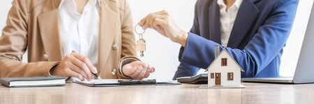 Real estate agent holding a key and asking costumer for contract to buy, get insurance or loan real...
