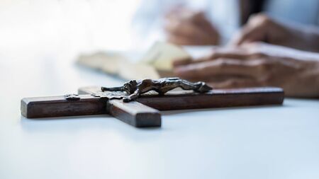 Christian woman praying with hands together on holy bible and wooden cross. Woman pray for god blessing to wishing have a better life and believe in goodness.の写真素材