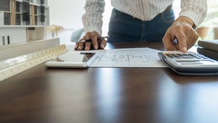 Architect or Engineer working in office with engineering tools, blueprint and building model. Construction concept.の写真素材