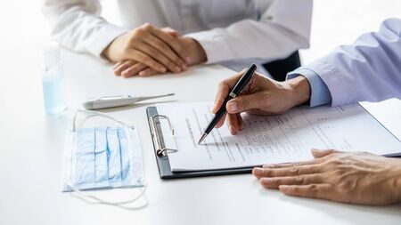 Asian woman filling a coronavirus self reporting form with a doctor recommended at hospital. Medical...