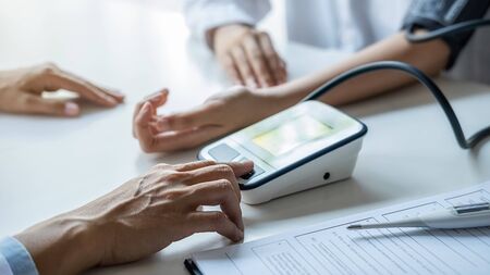 Doctor measuring patient blood pressure in clinic or hospital office. Medical and Health concept.