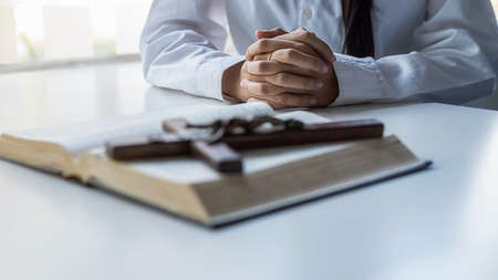 Christian woman praying on holy bible and wooden cross. Woman pray for god blessing to wishing have a better life and believe in goodness.の写真素材