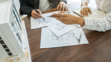 Engineer or architect teamwork working on construction project with building model and blueprint in...