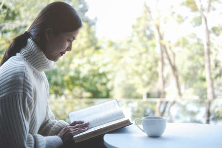 Asian woman reading a book in morning with soft morning light. Morning lifestyle concept.の写真素材