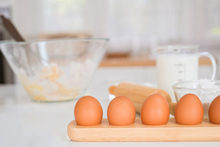 Eggs on a wooden cutting board with flour and eggs in the backgroundの写真素材