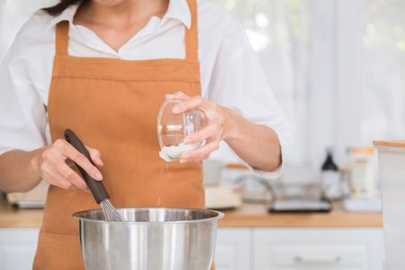 Close-up of female hands whisking eggs in the kitchen.の写真素材