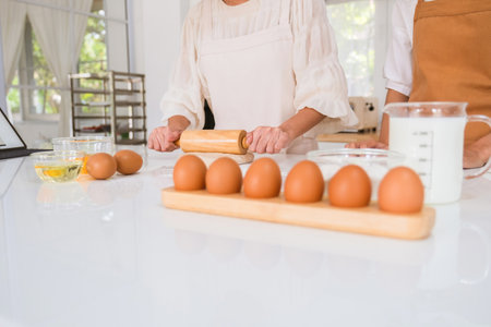 Mid section of senior woman rolling dough with rolling pin in kitchen at homeの写真素材