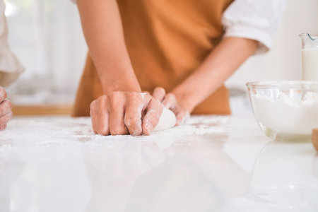 Close-up of female hands kneading dough in the kitchen