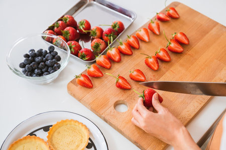 cropped shot of woman cutting strawberries on wooden cutting board with knifeの写真素材