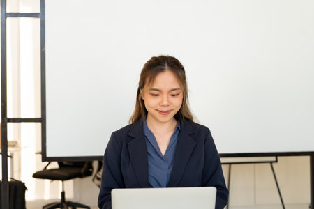 Businesswoman sitting at desk on couch in workplace or at home working on laptop and analyzing data...