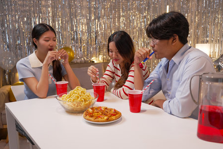 asian family eating pizza and drinking soda in christmas time at home