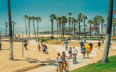 Los Angeles/California/USA - 07.22.2013: People riding on the bike over bicycle track between sand among palm trees on the sunny day with the blue sky.のeditorial素材