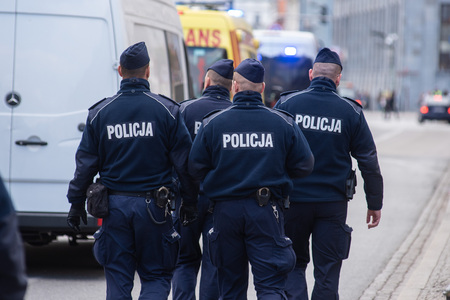 Group of police officers marching on the street. Dressed in blue uniforms with the police sign.