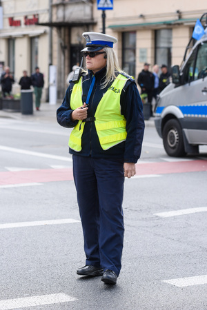 Warsaw / Poland - October.02.2018: Police woman standing on the cross road and controlling the traffic. Dressed in a police uniform with yellow west.のeditorial素材