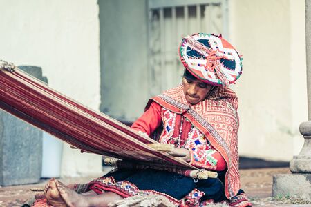 Cusco / Peru - May 26.2008: Portrait of a sewer woman, seamstress at work, dressed up in traditional native peruvian clothes. Seating on the street and holding the canvas and sewing tools.のeditorial素材