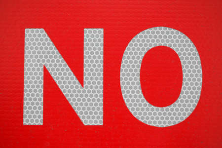 Sign that spells NO with white reflective letters on a textured red background. Close-up and full frame.の写真素材