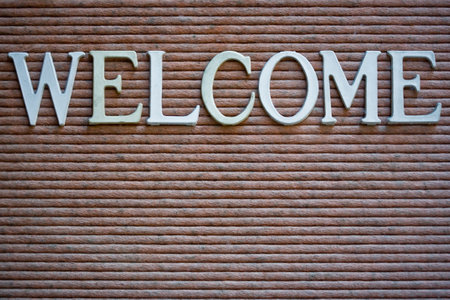 Display case sign that spells out WELCOME. Close-up, full frame, white and faded white letters on a pinkish gray background.の写真素材
