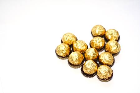 Gold wrapped expensive chocolate forming a heart shape. Space for copy-text. Intentional Shallow DOF.の写真素材
