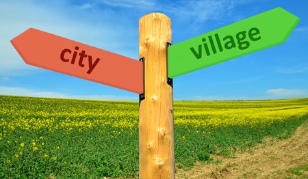Signpost with the label City and Village with a rape field in the backgroundの写真素材