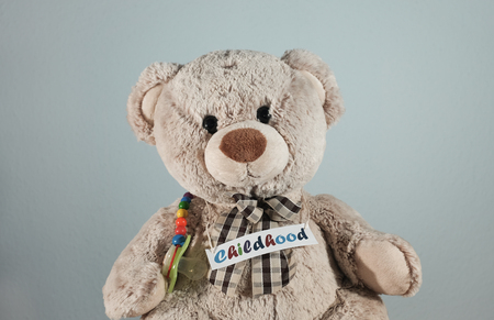 A cute teddy bear with a pacifier and the headline "Childhood"の写真素材