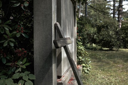An old decayed cross leans against a grave
