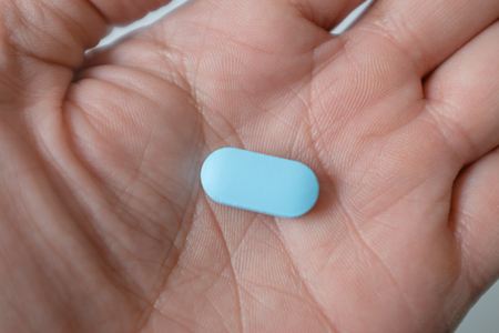 A male hand holds a blue pillの写真素材