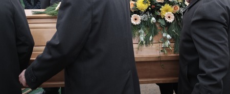 Pallbearers carry a coffin decorated with flowersの写真素材