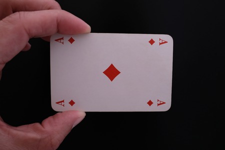 A male hand with ace of diamonds over black backgroundの写真素材