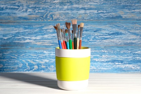 Paintbrush in mug in front of a rustic, blue wall in the backgroundの写真素材