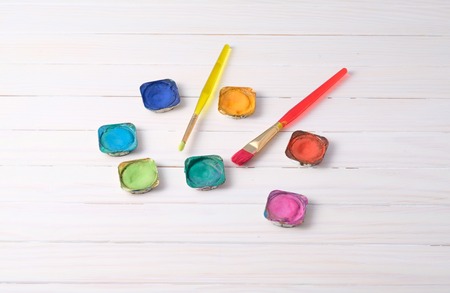 Paint brush with watercolor paints on white wooden padの写真素材