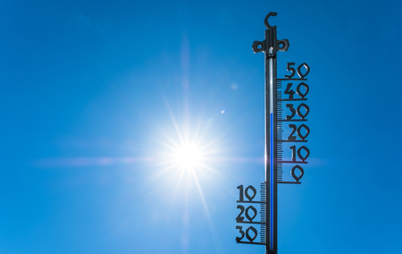 A Themometer with over 30 degrees mark with scorching sun in the background