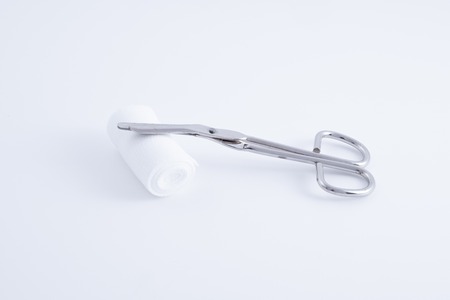 A medical scissors made of stainless steel with bandage over white background