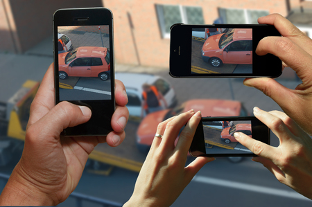 Curious gazers use smartphones to film a car while towing