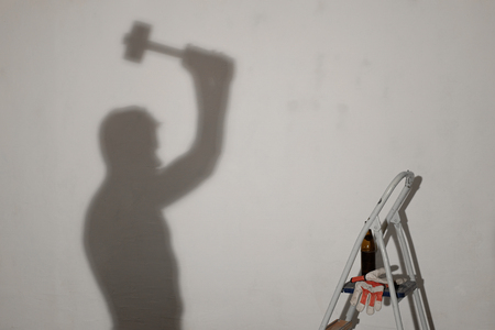 Silhouette of a worker with the hammer as a shadow on the wallの写真素材