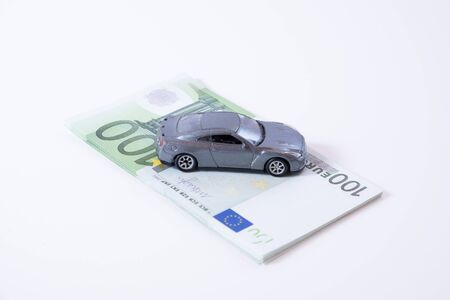 A silver car on a stack of 100 euro billsの写真素材
