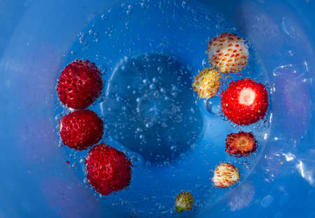 Sparkling mineral water in a blue mug with small strawberries.