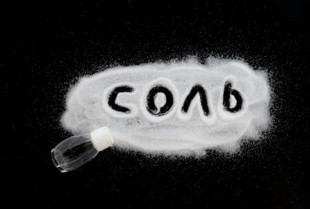 Handwritten word "Salt" (in Russian "ÑÐ¾Ð»Ñ") in a pile scattered on the black background.の写真素材