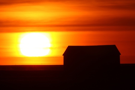 Setting sun backlighting farm buildingsの写真素材