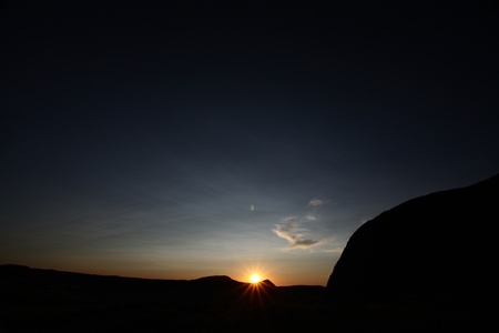 Sun setting behind a riseの写真素材