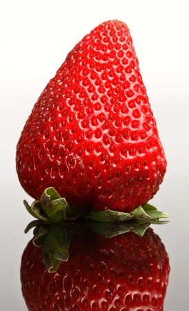 Whole strawberry reflected on glassの写真素材