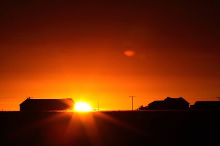 Sun rising behind a Saskatchewan farm buildingの写真素材