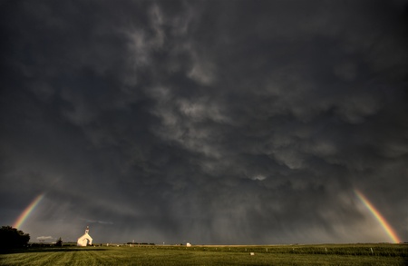 Old Country Church under stormy clouds and rainbowの写真素材
