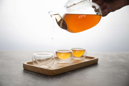 The hot tea is poured into a transparent cup on a white background.の写真素材