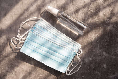 Face mask and alcohol bottle on Gray marble backgroundの写真素材