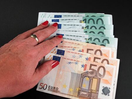 female hand with red finger nails on euro money